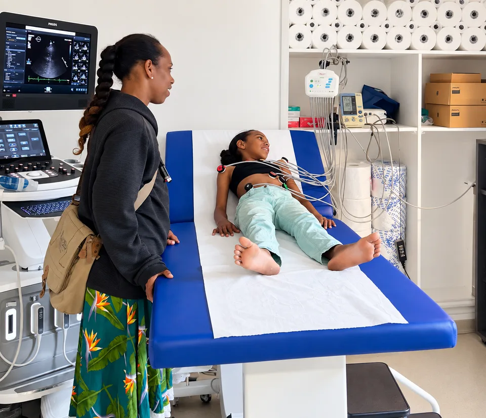 Une jeune patiente allongée pour un ECG, avec les électrodes en place et sa maman à ses côtés.